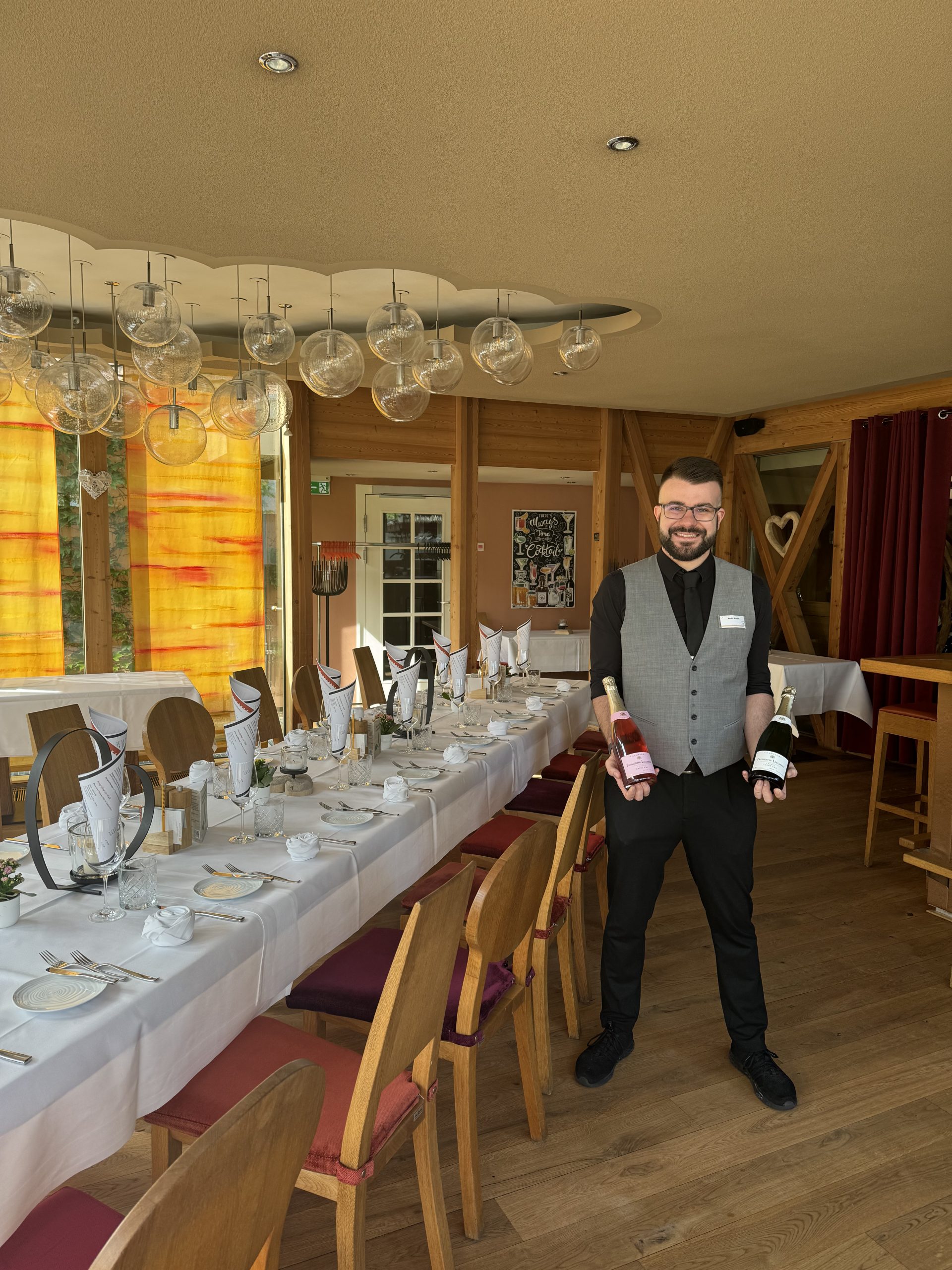 Moderne Holzfassade des Schindlerhof-Gebäudes mit orangenem Akzent und umgebendem Grün