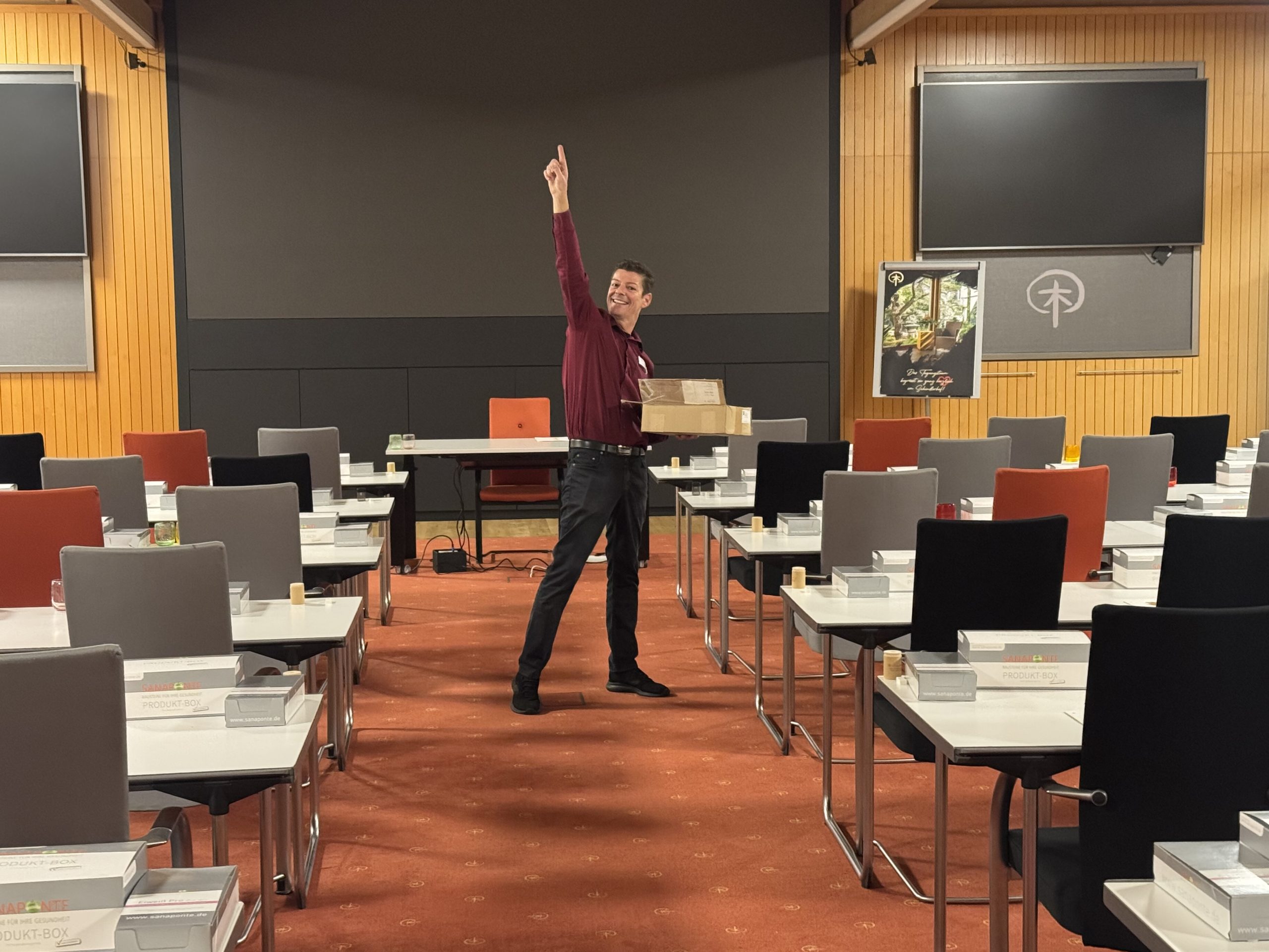 Moderne Holzfassade des Schindlerhof-Gebäudes mit orangenem Akzent und umgebendem Grün