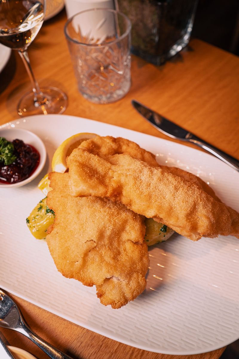 Moderne Holzfassade des Schindlerhof-Gebäudes mit orangenem Akzent und umgebendem Grün