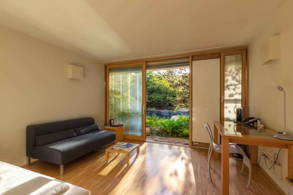 TEMBO_Schindlerhof_1024-3 Moderne Holzfassade des Schindlerhof-Gebäudes mit orangenem Akzent und umgebendem Grün