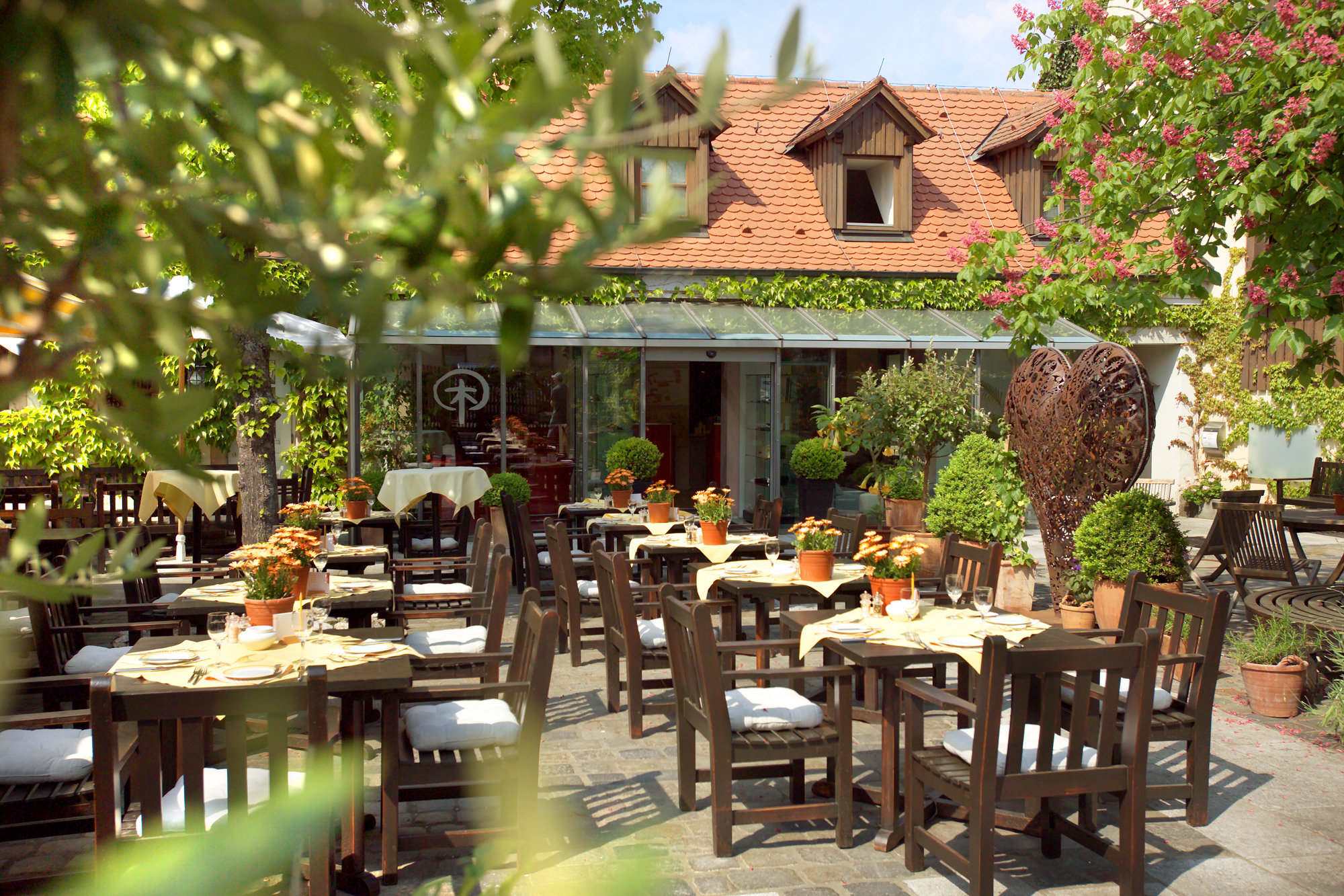 Gartenbild Moderne Holzfassade des Schindlerhof-Gebäudes mit orangenem Akzent und umgebendem Grün